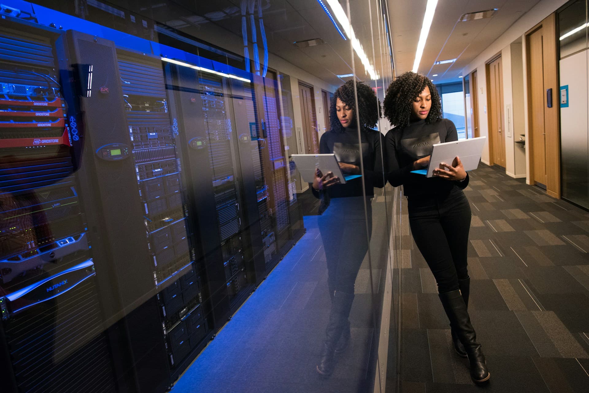 Person standing against glass window of server room.